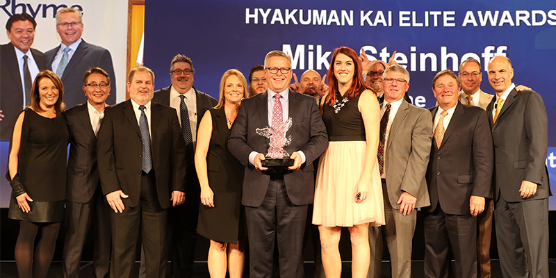 Rhyme employees pose around the Hyakuman Kai Elite Dealer Award