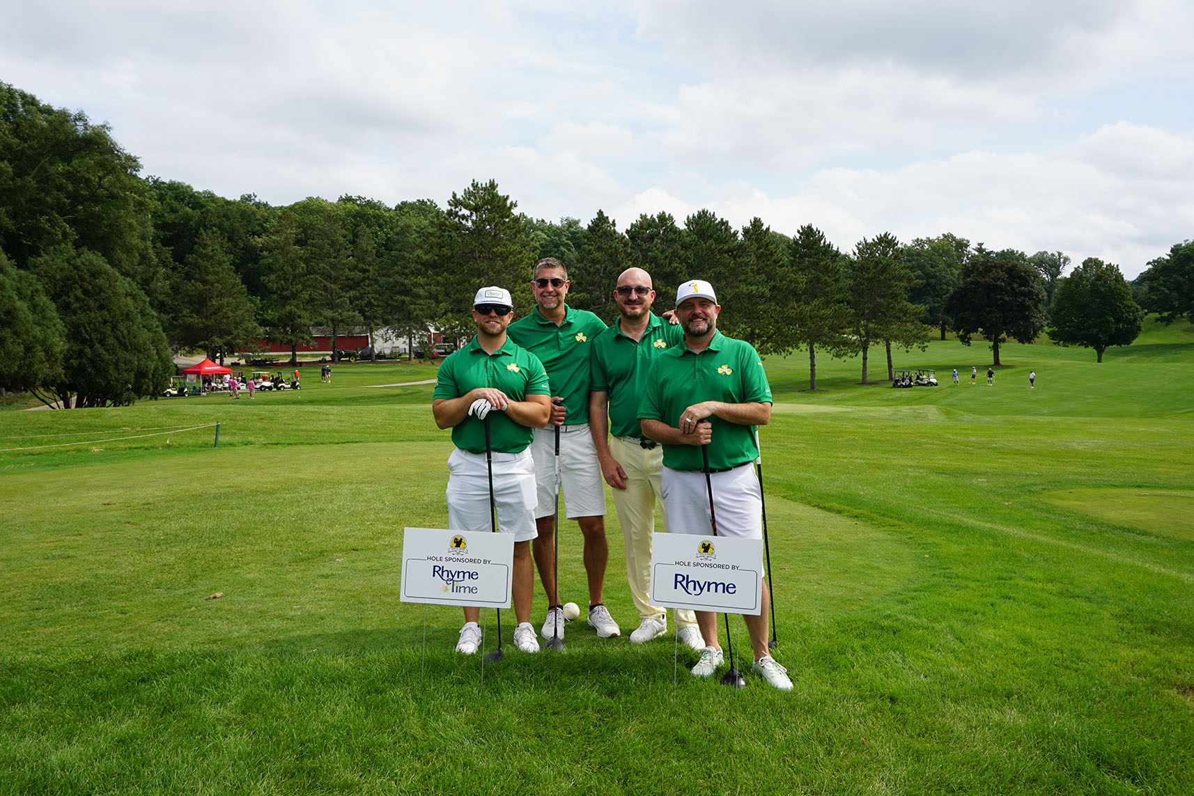 Four golfers stand next to Rhyme President behind a Rhyme Time Scholarship sign